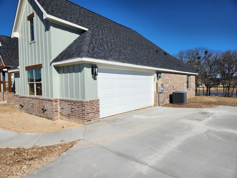 View of side of home with a garage and central AC unit