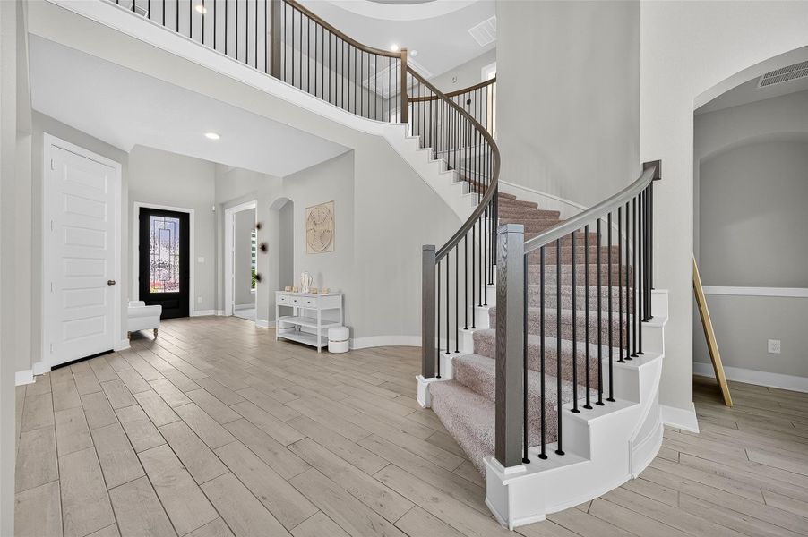 A graceful staircase leads to the upper level, beautifully showcased by the airy two-story entryway. Modern finishes and clean lines highlight the home's refined character.