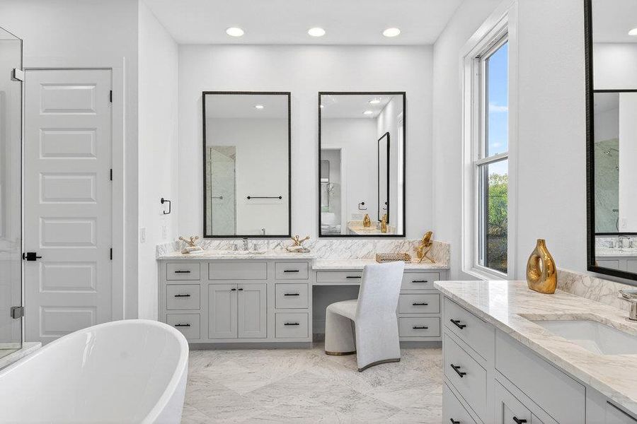 Full bathroom with a soaking tub, two vanities, recessed lighting, and light marble finish flooring