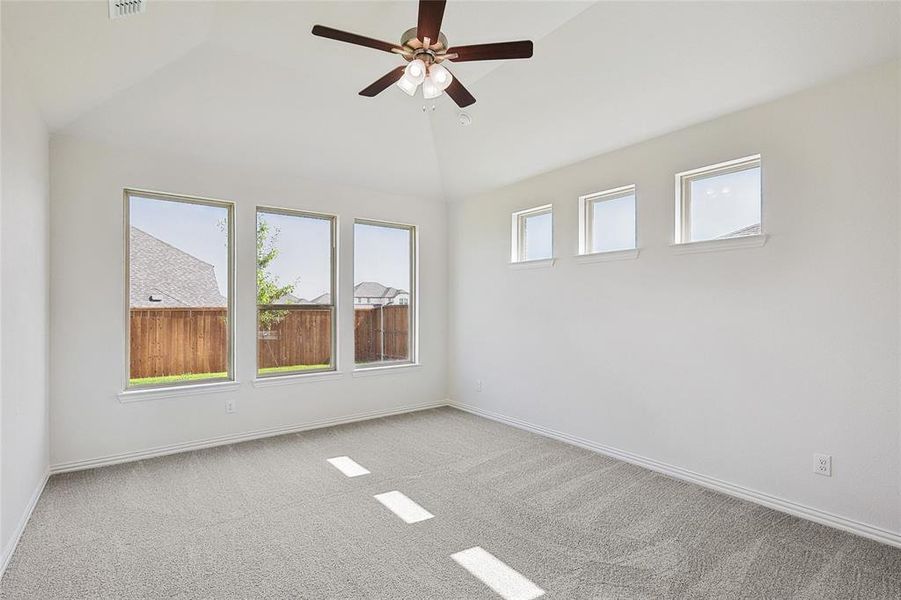 Carpeted spare room featuring high vaulted ceiling and ceiling fan