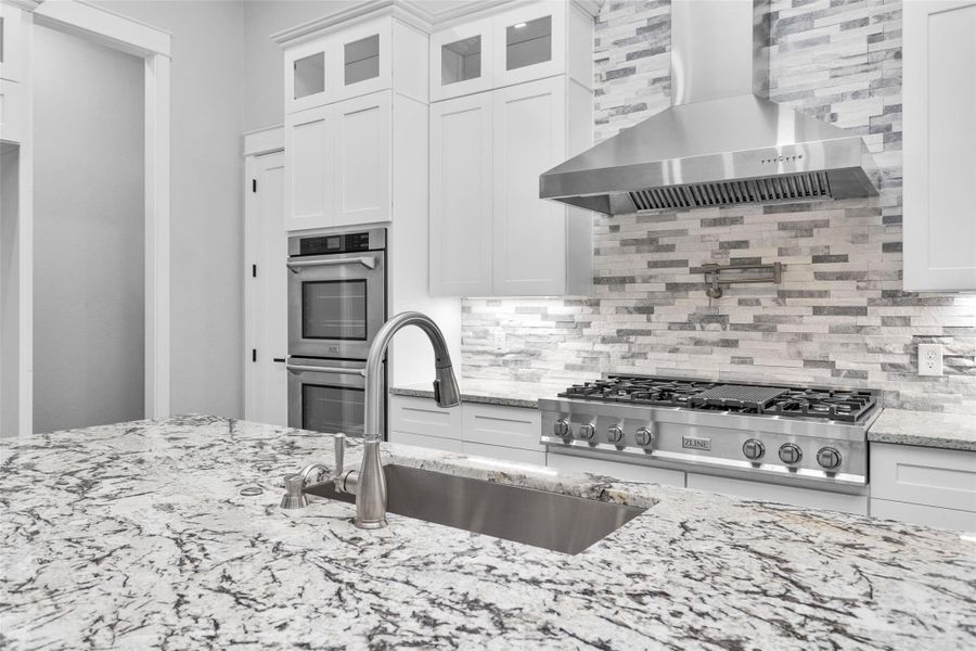 This Kitchen is equipped and/or has space for every modern convenience w/ a large island, loads of storage & cabinets double-ovens; a 6-burner gas range w/ a griddle, a Delta pot-filler, commercial hood & tile backsplash that runs to the ceiling.