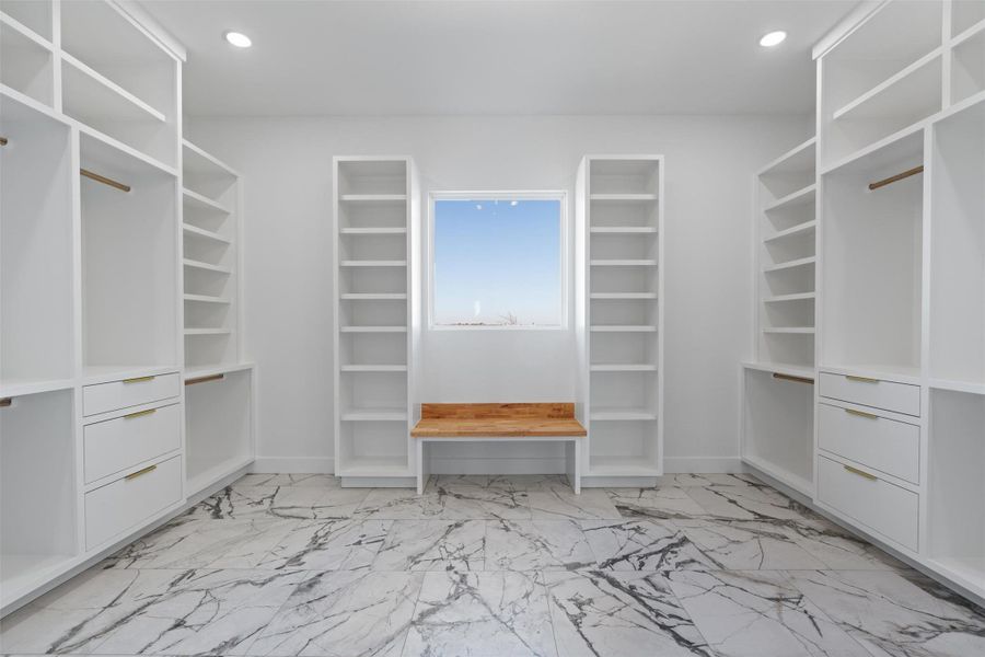 A well-lit walk-in closet offers ample storage with custom shelving and drawer units. A well-lit walk-in closet offers ample storage with custom shelving and drawer units.