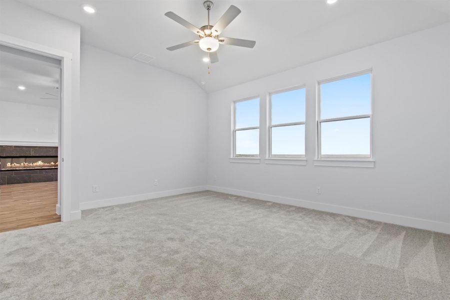 Empty room featuring carpet, ceiling fan, and vaulted ceiling