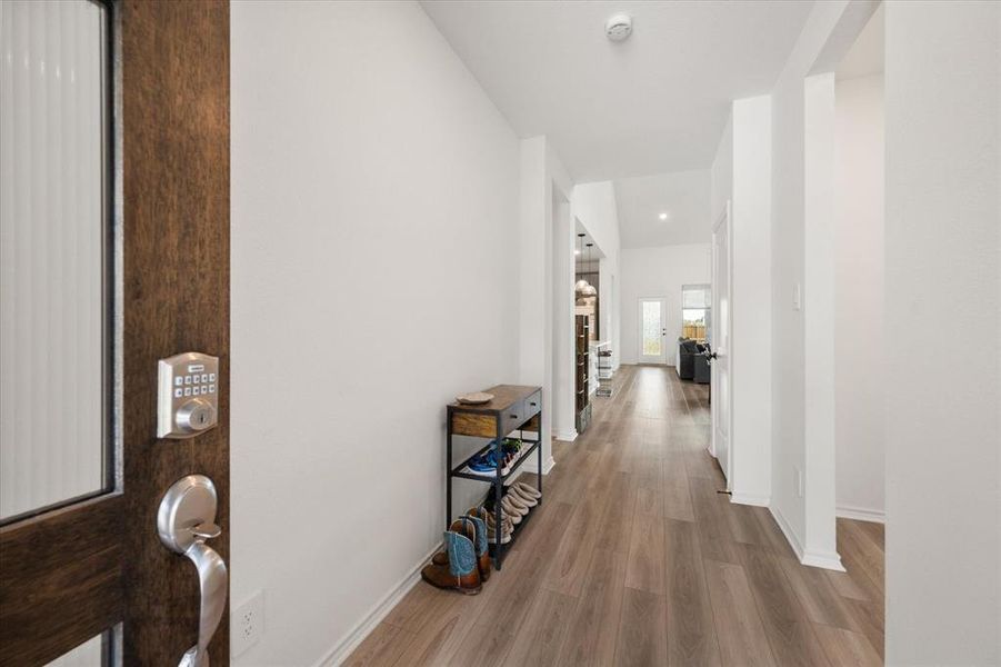 Inviting entryway featuring a dark wood-finish door with frosted glass panel and smart lock system