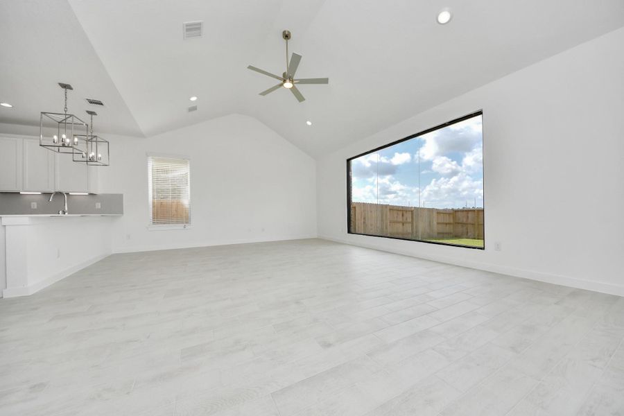 Relax and unwind in this inviting family room, illuminated by abundant natural light streaming in through tall windows, complemented by high ceilings and stunning flooring. Stay comfortable year-round with the gentle breeze from the ceiling fan, creating the perfect atmosphere for family gatherings.