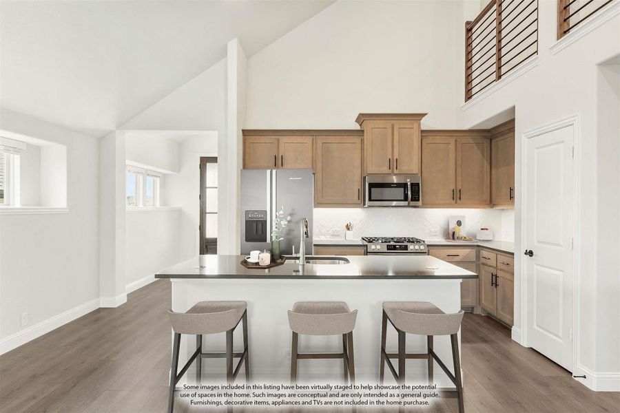 Kitchen with center island, three bar stools, light wood cabinets, and stainless steel appliances under vaulted ceiling Kitchen with center island, three bar stools, light wood cabinets, and stainless steel appliances under vaulted ceiling