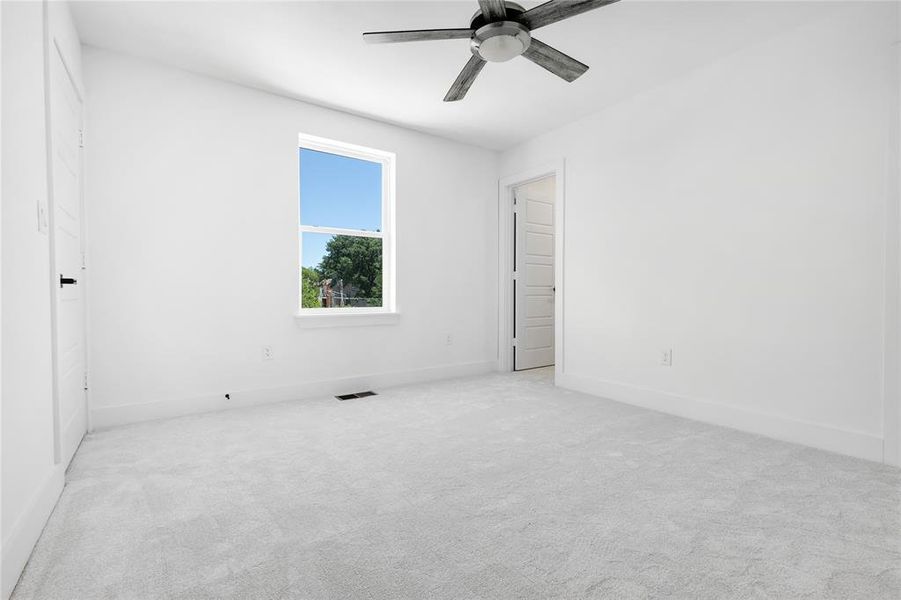 Carpeted spare room featuring ceiling fan