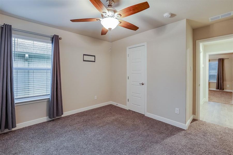 Carpeted empty room with plenty of natural light and a ceiling fan Carpeted empty room with plenty of natural light and a ceiling fan