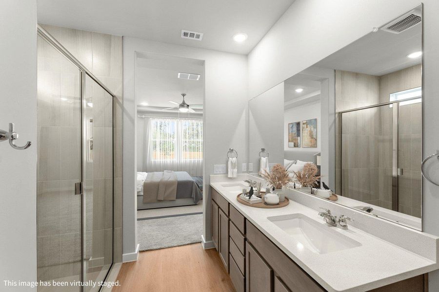 Modern primary bathroom featuring dual vanities, a glass-enclosed shower, and convenient access to a sun-filled bedroom. Modern primary bathroom featuring dual vanities, a glass-enclosed shower, and convenient access to a sun-filled bedroom.