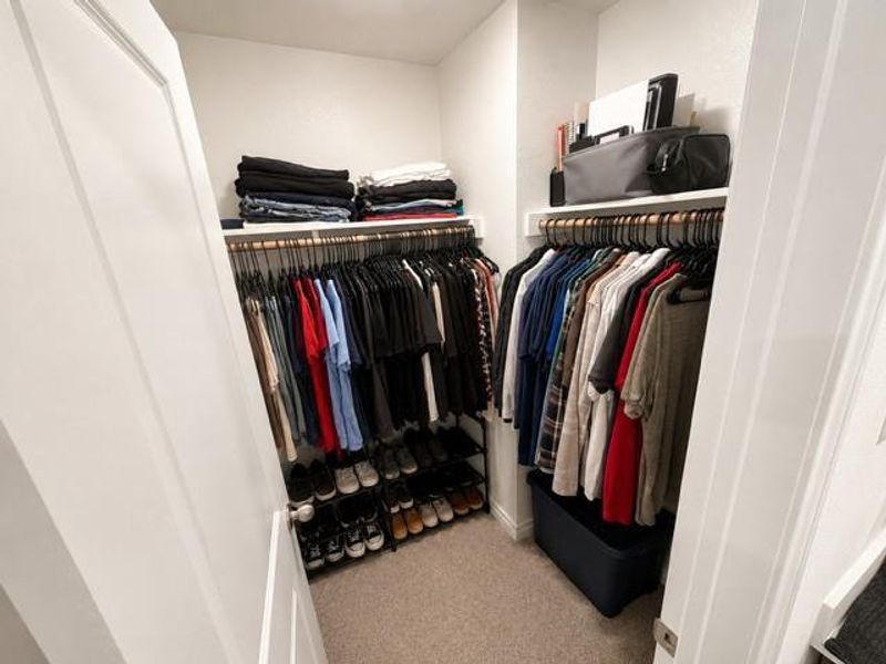 Walk-in closet featuring white interior walls, wood-finish shelving, and integrated hanging rods Walk-in closet featuring white interior walls, wood-finish shelving, and integrated hanging rods