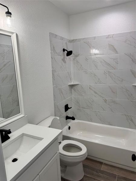 Full bathroom featuring vanity, toilet, and tiled shower / bath combo