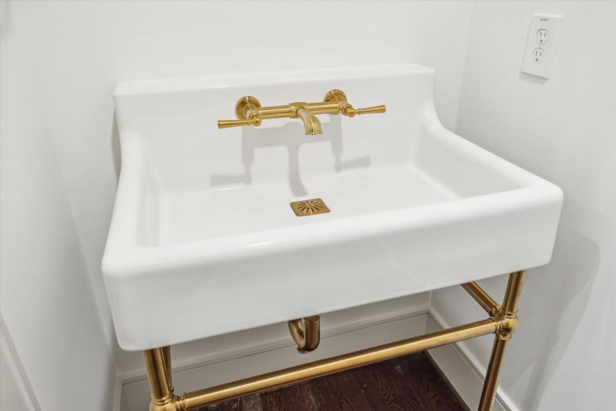 Powder Bath features console sink with brass details.