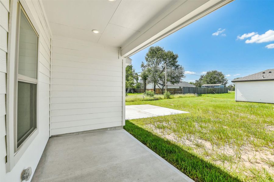 Covered back patio with recessed lighting offers a shaded space to relax and enjoy the backyard.
