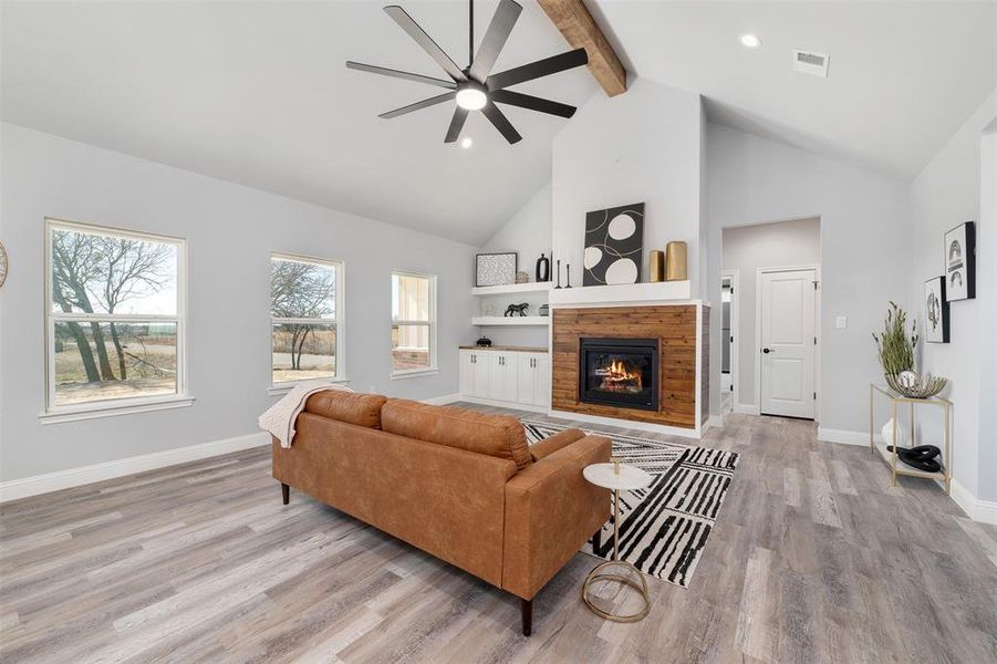 Living room with ceiling fan, beam ceiling, high vaulted ceiling, and light wood-type flooring