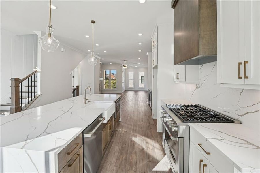 Kitchen with white cabinetry, light stone countertops, a large island, dark wood-type flooring, and recessed lighting