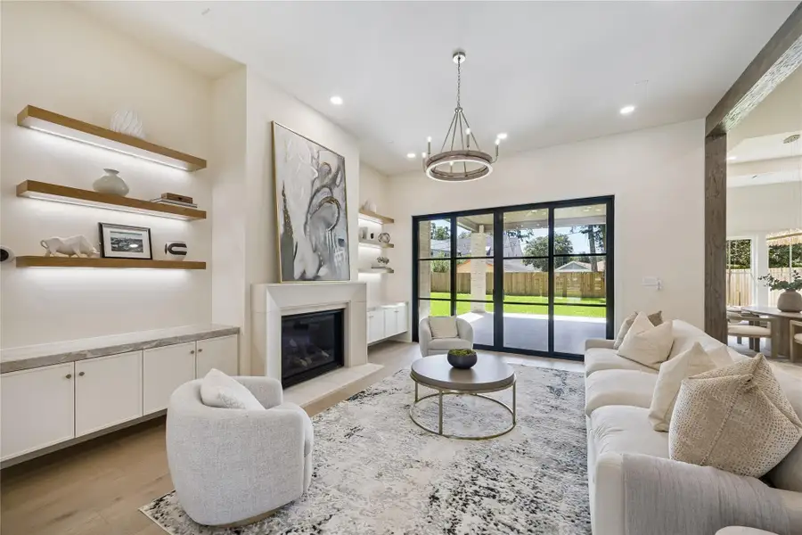 LIVING ROOM: There is an abundance of natural light from the wall of windows overlooking the backyard. The inviting living room features a gas fireplace, LED lit shelving, wide-plank white oak floors and is wired for surround sound.