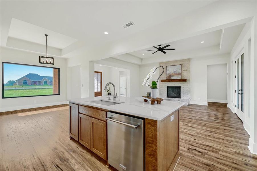 Kitchen featuring dishwasher, sink, a fireplace, and light wood-type flooring