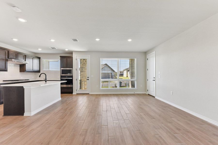 Kitchen with dark brown cabinetry, stainless steel appliances, light wood-type flooring, recessed lighting, and an island with sink