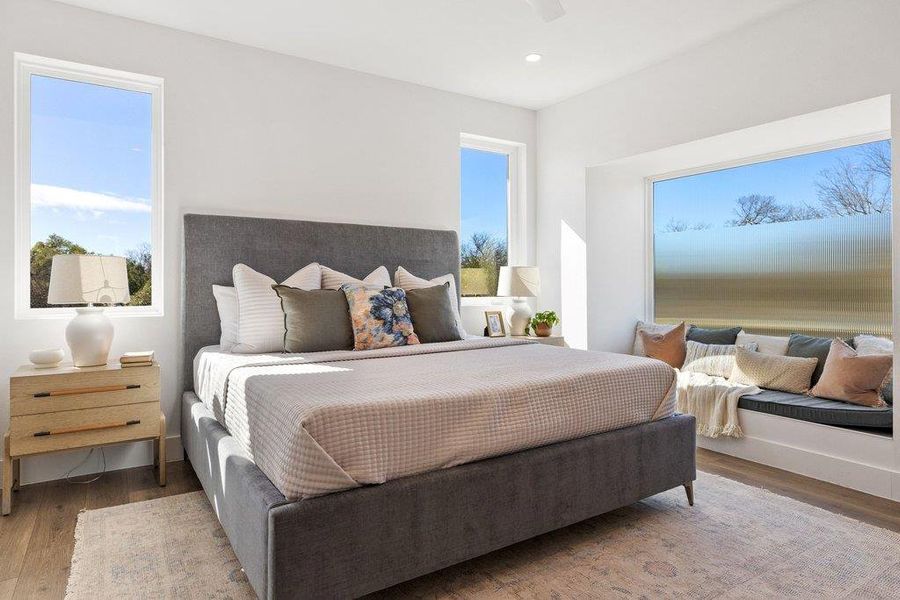 Primary bedroom with large bench and bay window plus hidden storage under seating, ceiling fan and recessed lighting with dimmers, fan
