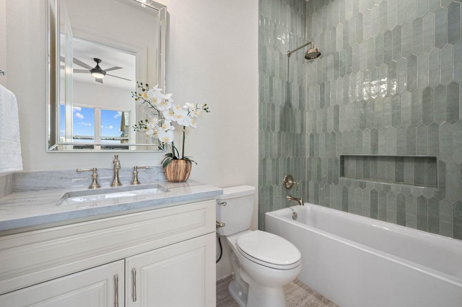Bathroom with washtub / shower combination, vanity, and a ceiling fan