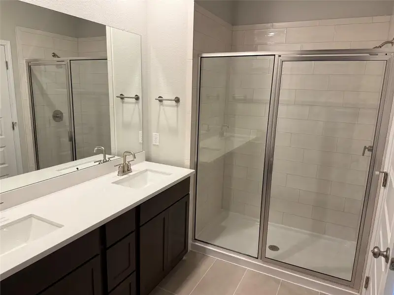 Full bath with a shower stall, double vanity, and light tile patterned flooring Full bath with a shower stall, double vanity, and light tile patterned flooring