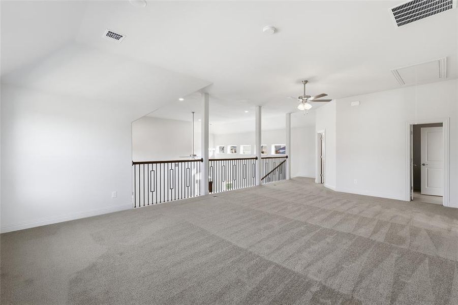 Carpeted empty room with attic access and ceiling fan