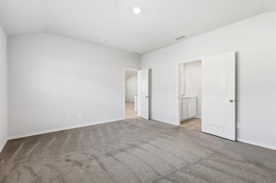 Carpeted room with entry to living, kitchen and dining and entry to ensuite bath Carpeted room with entry to living, kitchen and dining and entry to ensuite bath