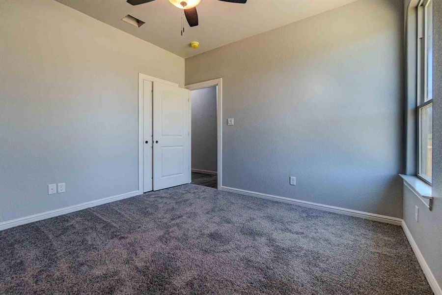 Carpeted empty room featuring baseboards and a ceiling fan Carpeted empty room featuring baseboards and a ceiling fan