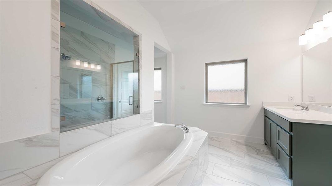 Bathroom with vanity, lofted ceiling, and shower with separate bathtub