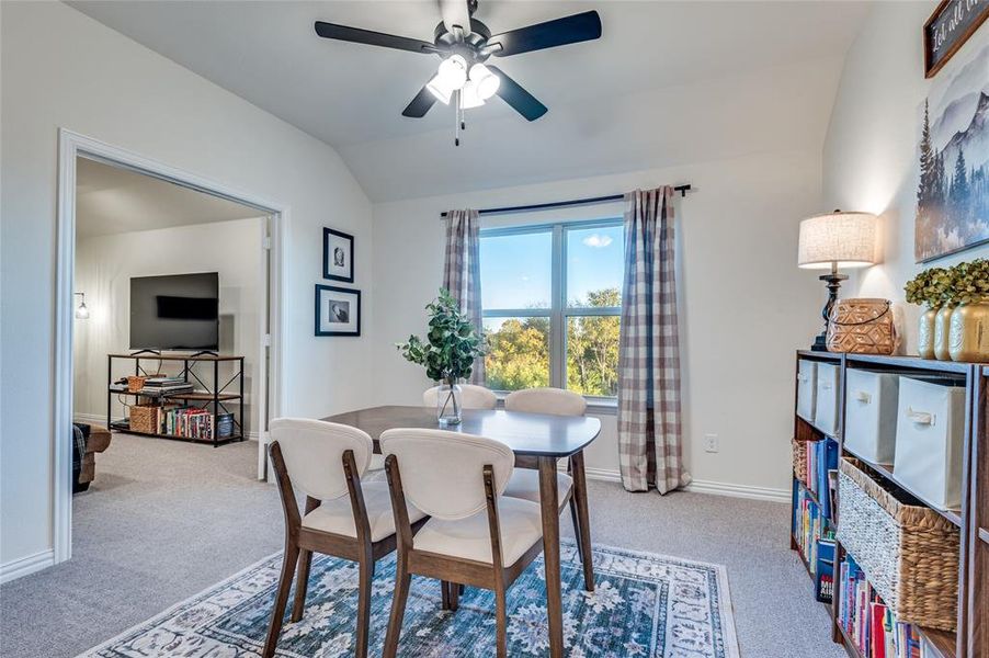 Dining room featuring lofted ceiling, carpet flooring, and a ceiling fan