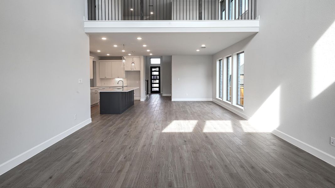 Unfurnished living room featuring recessed lighting, dark wood-type flooring, and a towering ceiling