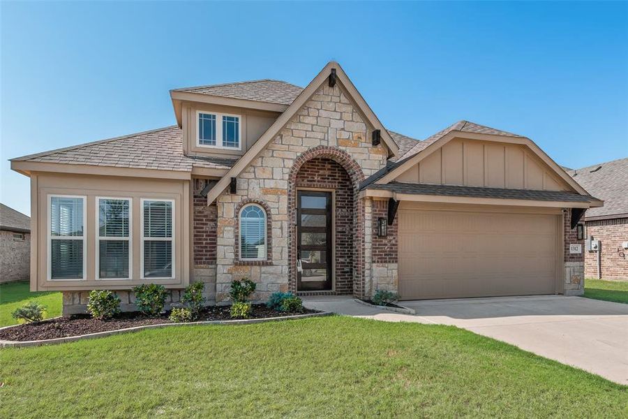 View of front facade with roof with shingles, stone siding, a front yard, and concrete driveway View of front facade with roof with shingles, stone siding, a front yard, and concrete driveway