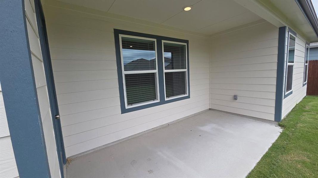 Covered patio with concrete flooring, recessed lighting, white horizontal siding, and dark trim windows Covered patio with concrete flooring, recessed lighting, white horizontal siding, and dark trim windows