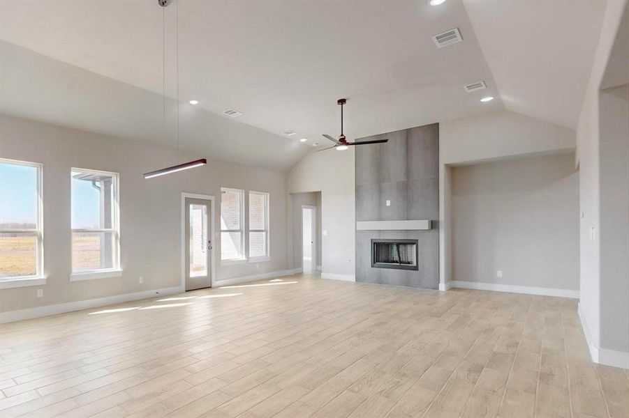 Unfurnished living room with plenty of natural light, a fireplace, light wood-type flooring, and ceiling fan