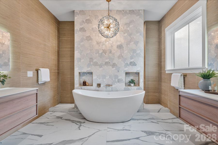 Stunning primary bathroom features a soaking tub centered against a custom accent wall with Walk through rain shower