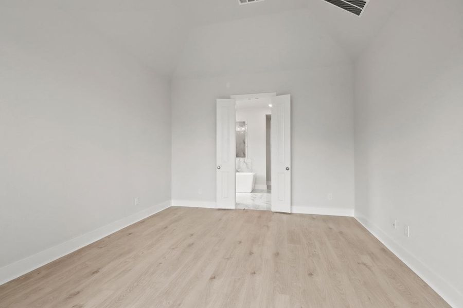 Unfurnished room featuring light wood finished floors, baseboards, and vaulted ceiling Unfurnished room featuring light wood finished floors, baseboards, and vaulted ceiling