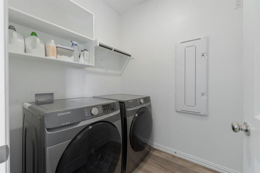 Washroom featuring separate washer and dryer, electric panel, and hardwood / wood-style flooring