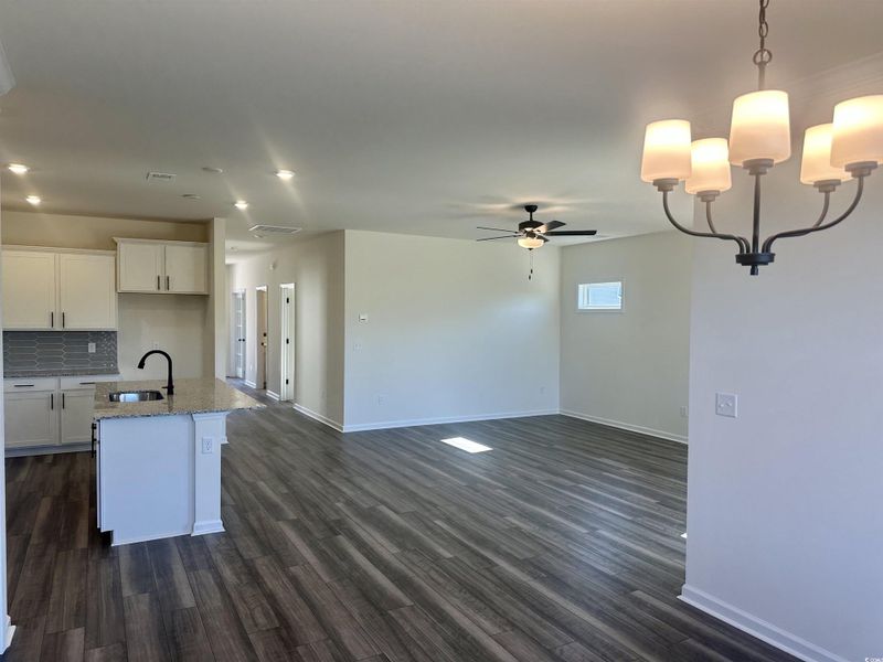 Kitchen with white cabinetry, an island with sink, pendant lighting, granite countertops, beautiful back splash and dark wood finished floors Kitchen with white cabinetry, an island with sink, pendant lighting, granite countertops, beautiful back splash and dark wood finished floors