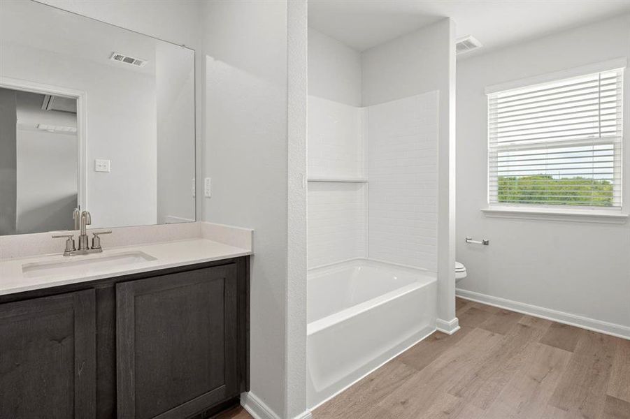 Bathroom featuring vanity, light wood finished floors, and  shower combination