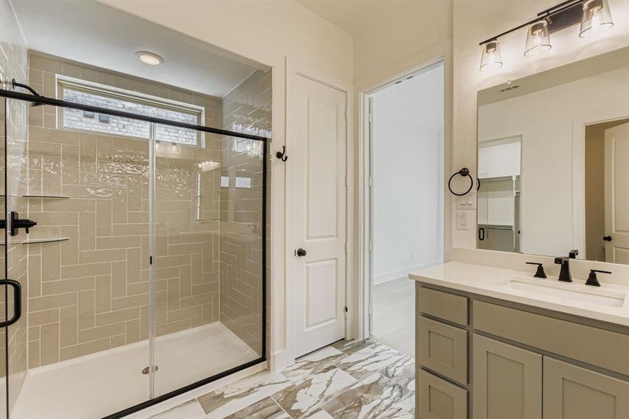Full bath featuring a stall shower, vanity, and marble look tiles Full bath featuring a stall shower, vanity, and marble look tiles