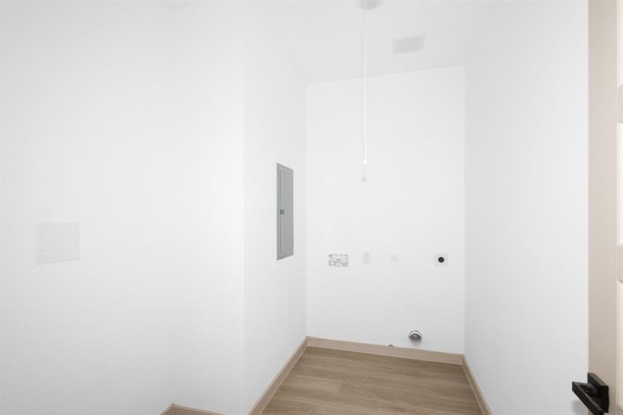 Laundry area featuring laundry area, light wood-style floors, electric panel, baseboards, and electric dryer hookup Laundry area featuring laundry area, light wood-style floors, electric panel, baseboards, and electric dryer hookup