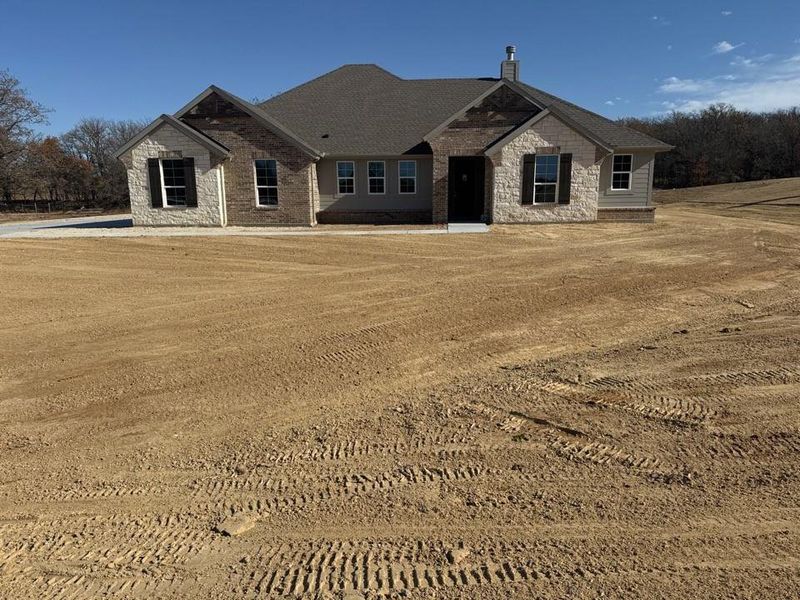View of front of property with stone siding, brick siding, and a shingled roof