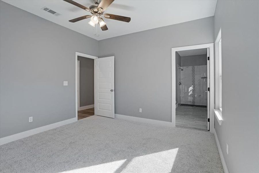 Unfurnished bedroom featuring connected bathroom, carpet flooring, and ceiling fan