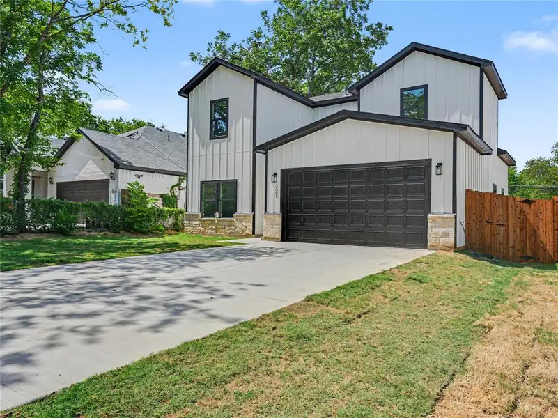 Contemporary exterior featuring vertical white siding, black trim, and a prominent dark garage door Contemporary exterior featuring vertical white siding, black trim, and a prominent dark garage door