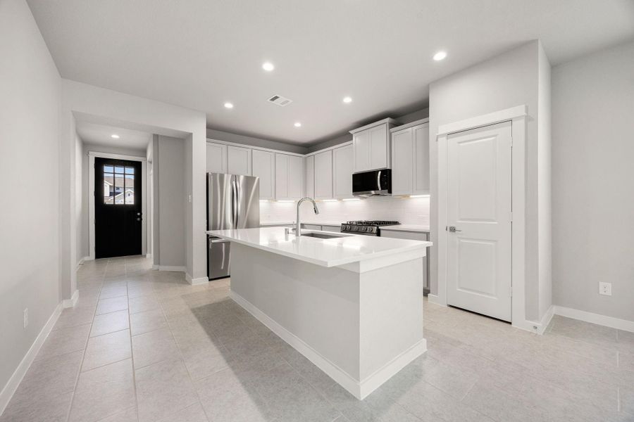 Kitchen with center island and breakfast bar, stainless appliances and open to the family room.