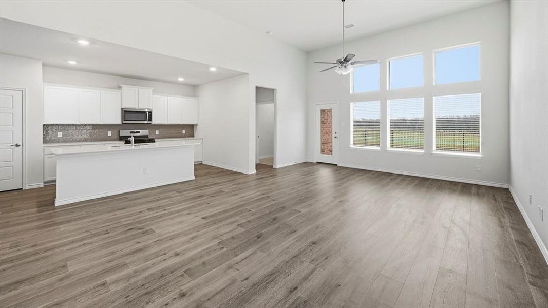 Open-concept living area featuring high ceilings, light wood-finish flooring, and a contemporary ceiling fan