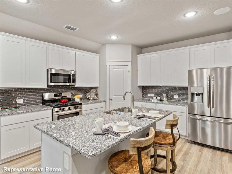 Open-concept kitchen featuring an island with ample counter space, stainless steel appliances, white cabinetry, a tile backsplash, and recessed lighting