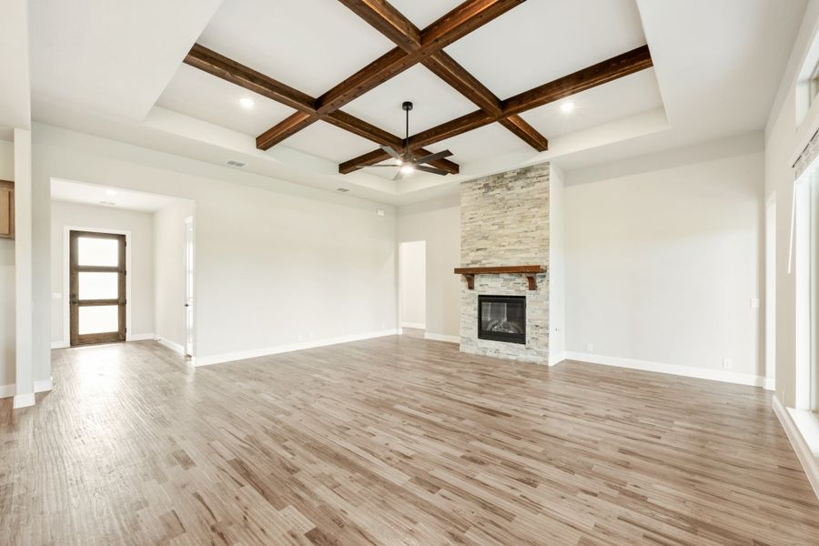Open living room with wood beam coffered ceiling, stone fireplace, and hardwood floors Open living room with wood beam coffered ceiling, stone fireplace, and hardwood floors