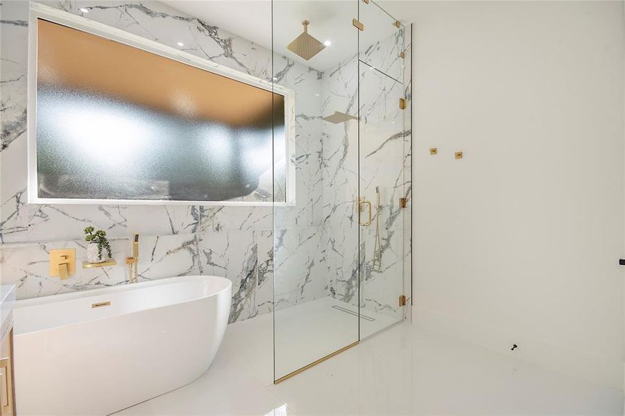 Bathroom with a marble finish shower, a freestanding bath, and tile walls Bathroom with a marble finish shower, a freestanding bath, and tile walls