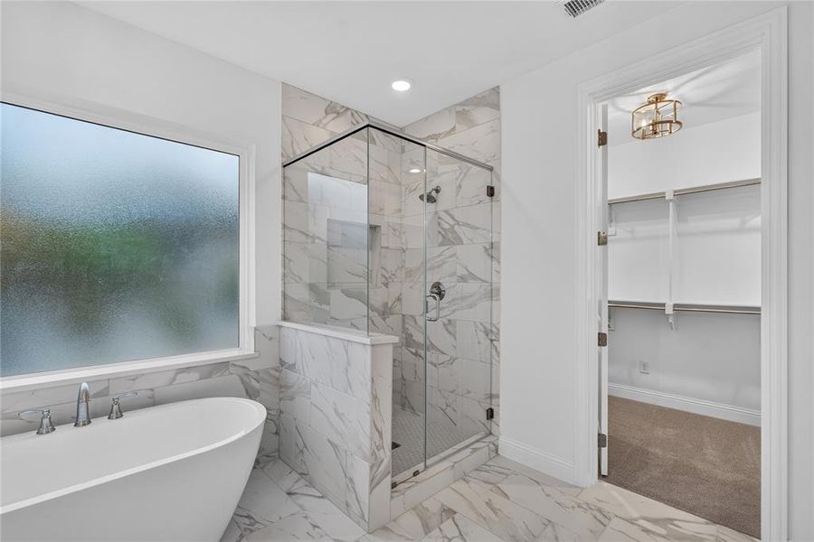 Bathroom featuring a freestanding tub, glass-enclosed shower, marble-finish tile flooring, recessed lighting, and a frosted window Bathroom featuring a freestanding tub, glass-enclosed shower, marble-finish tile flooring, recessed lighting, and a frosted window